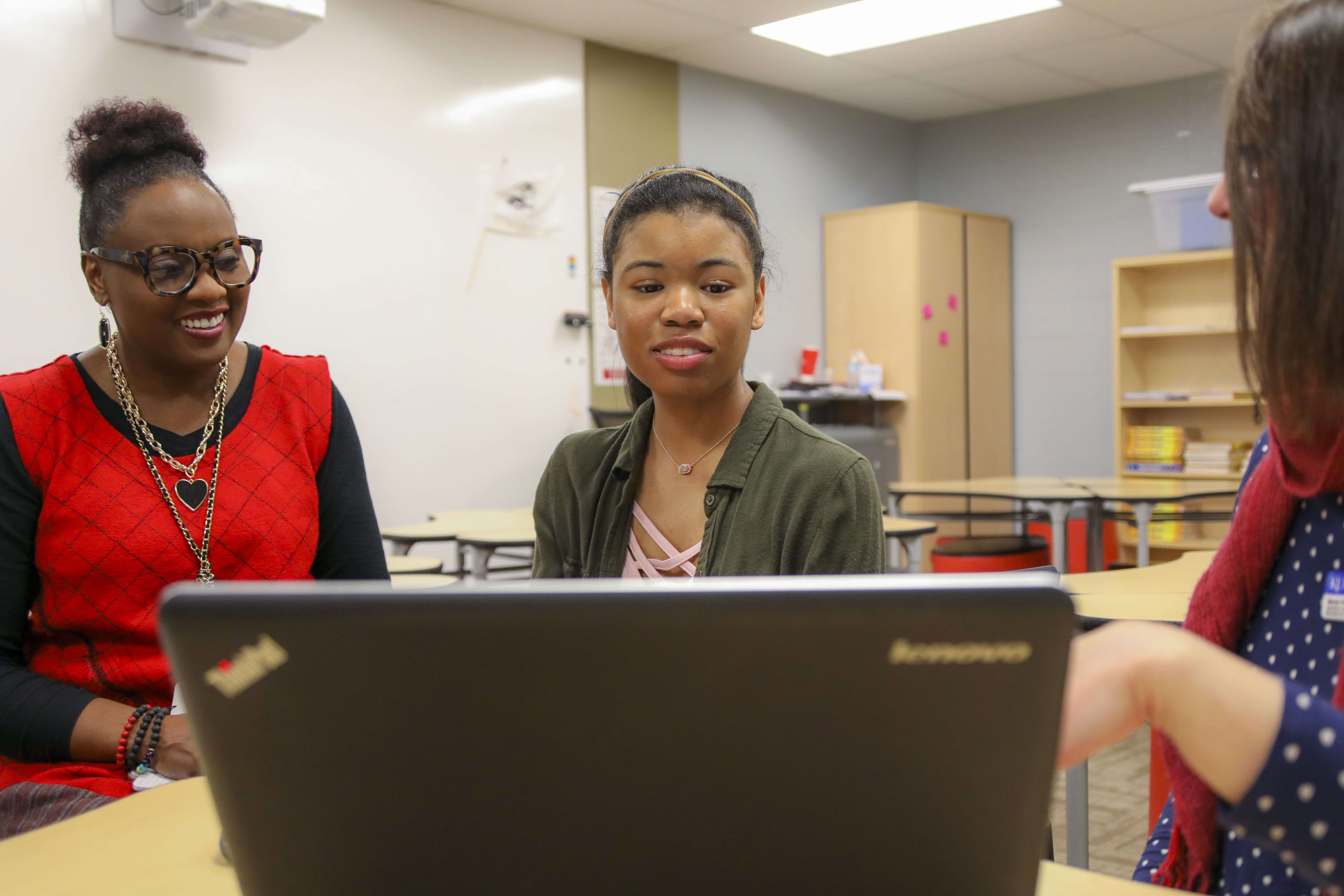 A TRIO advisor points at a computer with a student and parent smiling
